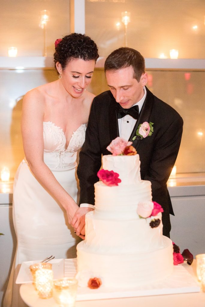 W Hoboken wedding photos by Mikkel Paige Photography. The bride and groom cut their white tiered wedding cake during their April event.