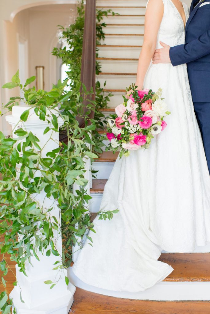 Photography of the bride's bouquet and staircase wrapped in greenery for a colorful day photographed by Mikkel Paige Photography. Floral arrangements created by Eclectic Sage for a wedding venue in Raleigh NC, Merrimon-Wynne.