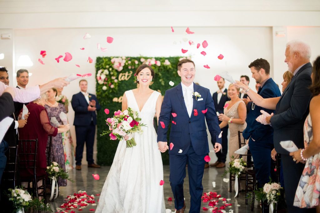 A photo of a colorful ceremony petal toss with the bride and groom at Merrimon-Wynne house, captured by Mikkel Paige Photography. This downtown wedding venue in Raleigh, NC is partially indoors and outdoors.