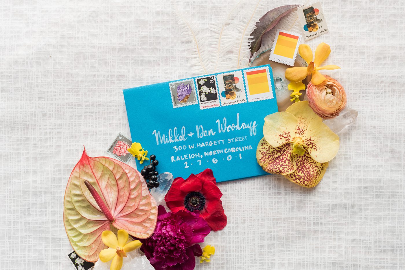 Flat lay styled photo and hand lettered envelope by Mikkel Paige Photography. This bright blue piece was part of an invitation that she styled with gemstone from her own intimate elopement wedding in downtown Raleigh, North Carolina.