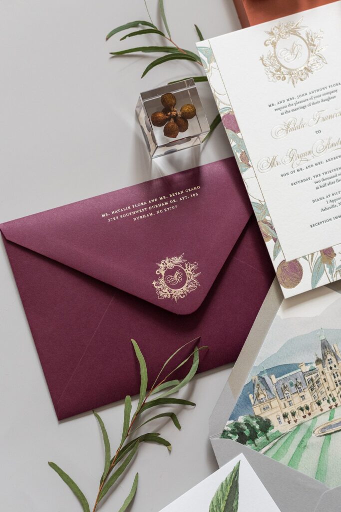 Stationery set flat lay photos by Mikkel Paige, with a merlot colored envelope with gold details for the return address and hand-painted envelope elements.