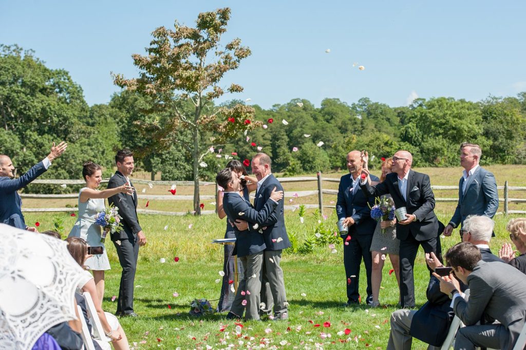Hamptons wedding photographer captures two grooms for a same sex wedding at a private home. Outdoor ceremony images with a petal toss by Mikkel Paige Photography.