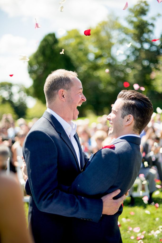 Hamptons wedding photographer captures two grooms for a same sex wedding at a private home. Outdoor ceremony images with a petal toss by Mikkel Paige Photography.