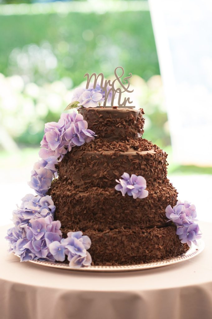 Hamptons wedding photographer captures two grooms for a same sex wedding at a private home with a chocolate shavings tiered cake with purple hydrangea and a 