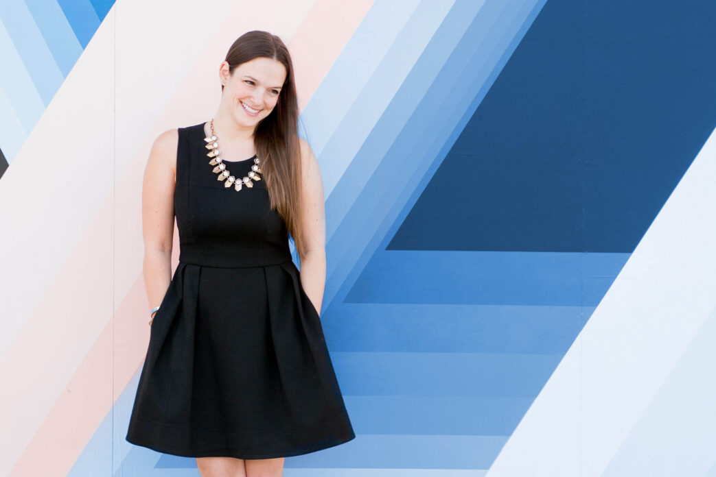 Mikkel Paige Photography photo of her against a blue and pinked striped wall.