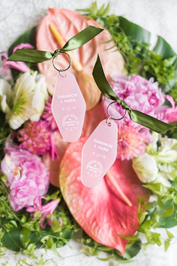 Flat lay styled photo by Mikkel Paige Photography of the key chains a bride and groom used as escort cards for their colorful wedding with tropical flowers at Highgrove Estate in North Carolina.