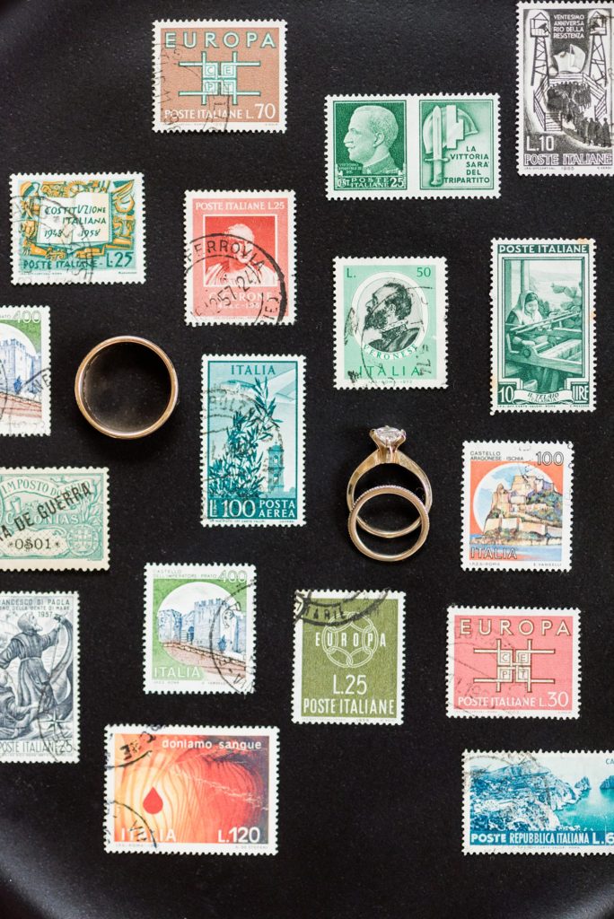 Flat lay photography of rings by destination and luxury wedding photographer Mikkel Paige Photography. Vintage stamps were styled by the photographer to create this memorable ring photo.