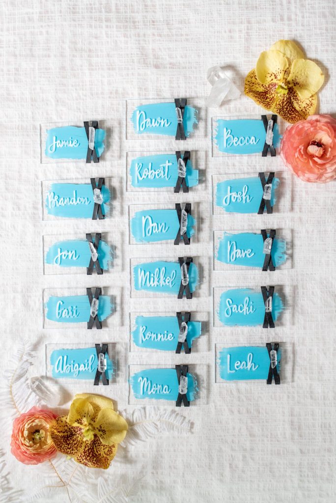 Flat lay styled photo by Mikkel Paige Photography of escort cards and crystals with bright colors for her own intimate elopement wedding dinner in downtown Raleigh, North Carolina.