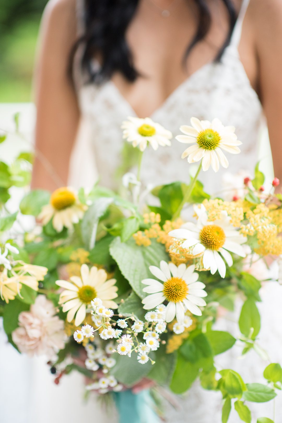 A wildflower bridal bouquet with berries, daisies and vines photographed by Mikkel Paige Photography and created by Mood Fleuriste. The couple eloped when COVID-19 changed their original plan. #mikkelpaige #wildflowerbouquet