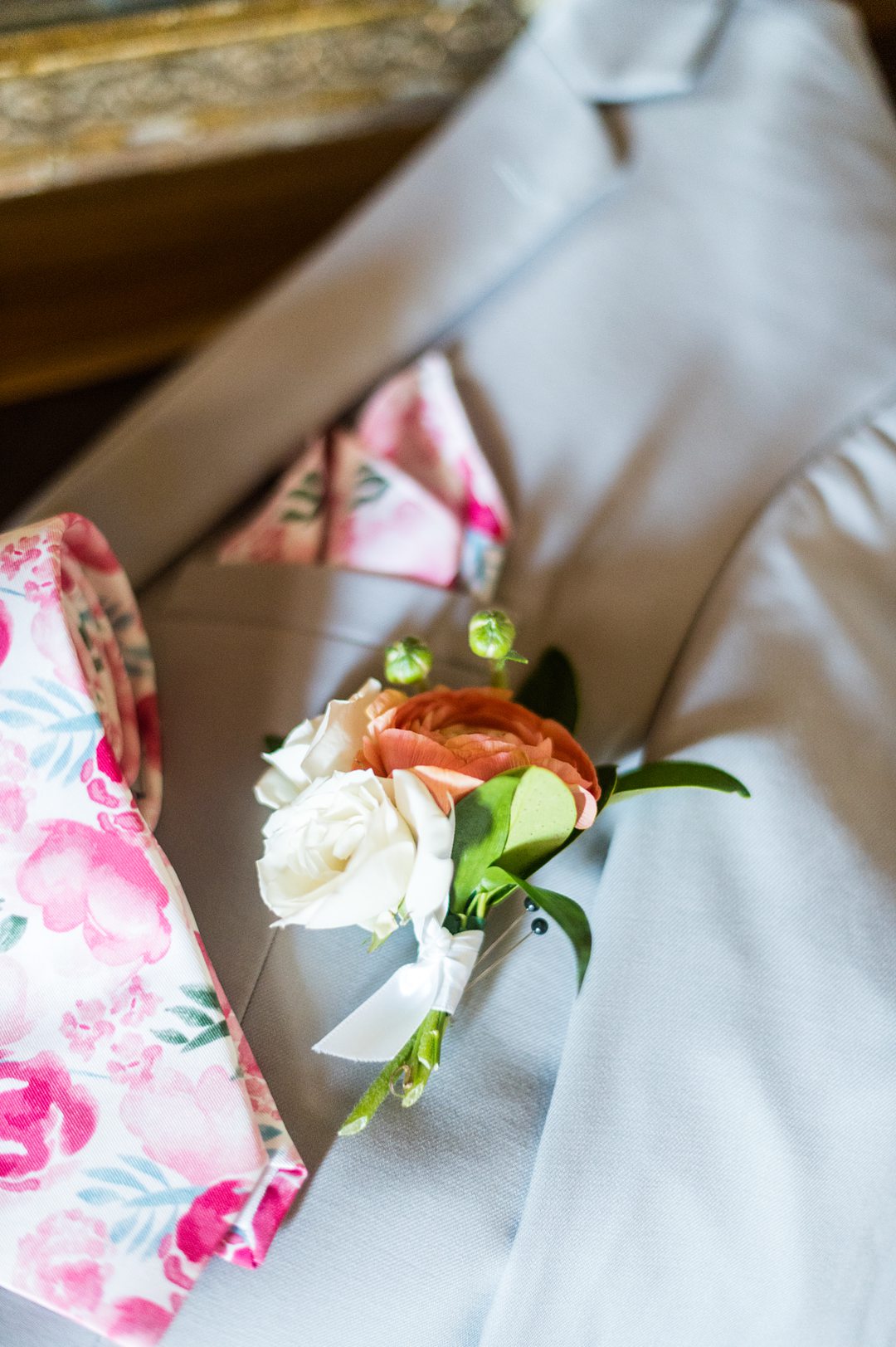 A ranunculus and spray rose boutonniere and pink floral tie and pocket square, for a small wedding in Charlottesville, VA during COVID. Photos by Mikkel Paige Photography.