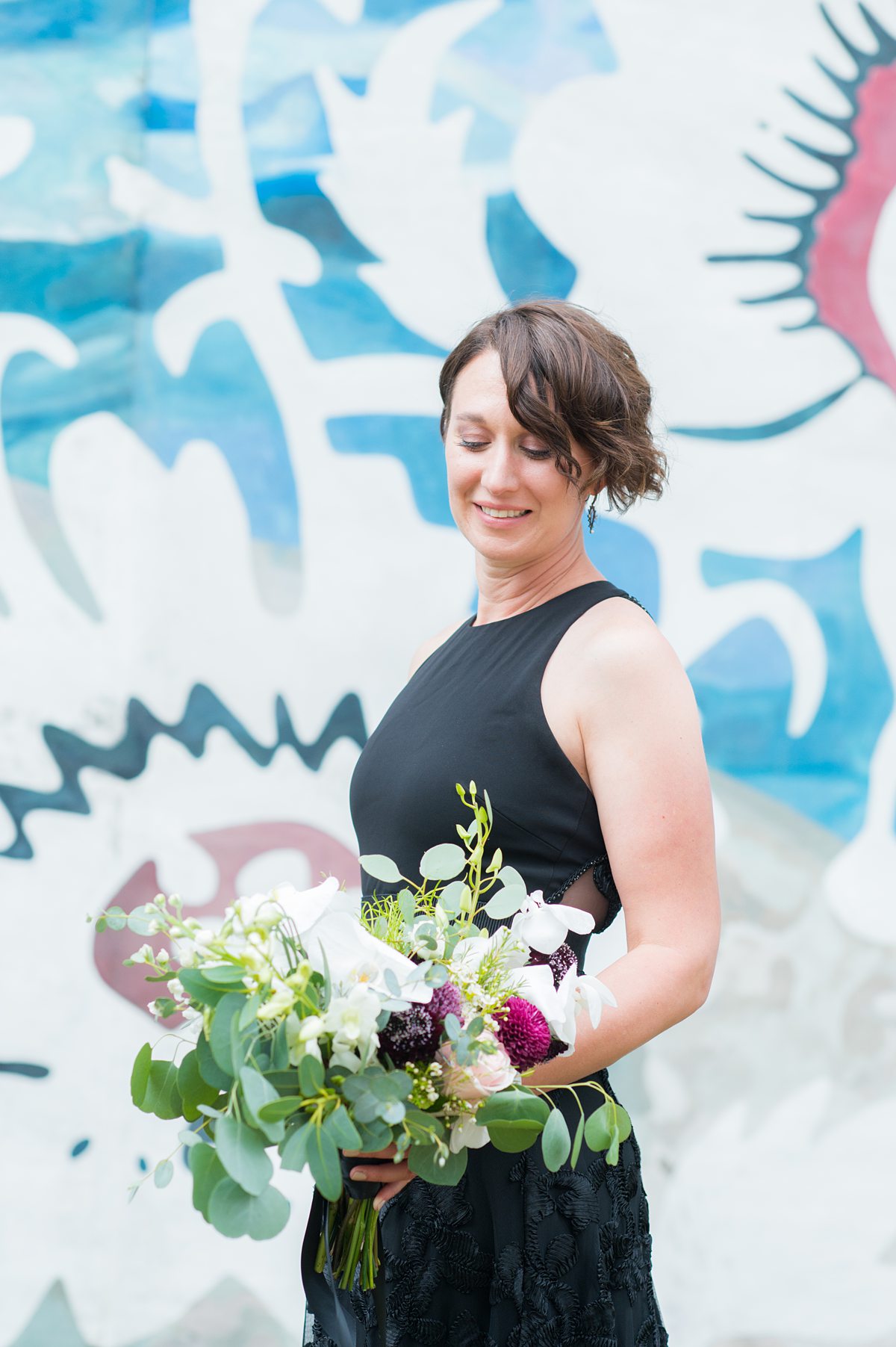 Bride in a black gown with colorful mural behind her.