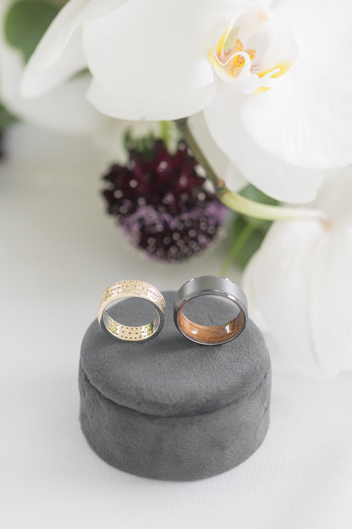 Wedding rings on a grey velvet round ring box.