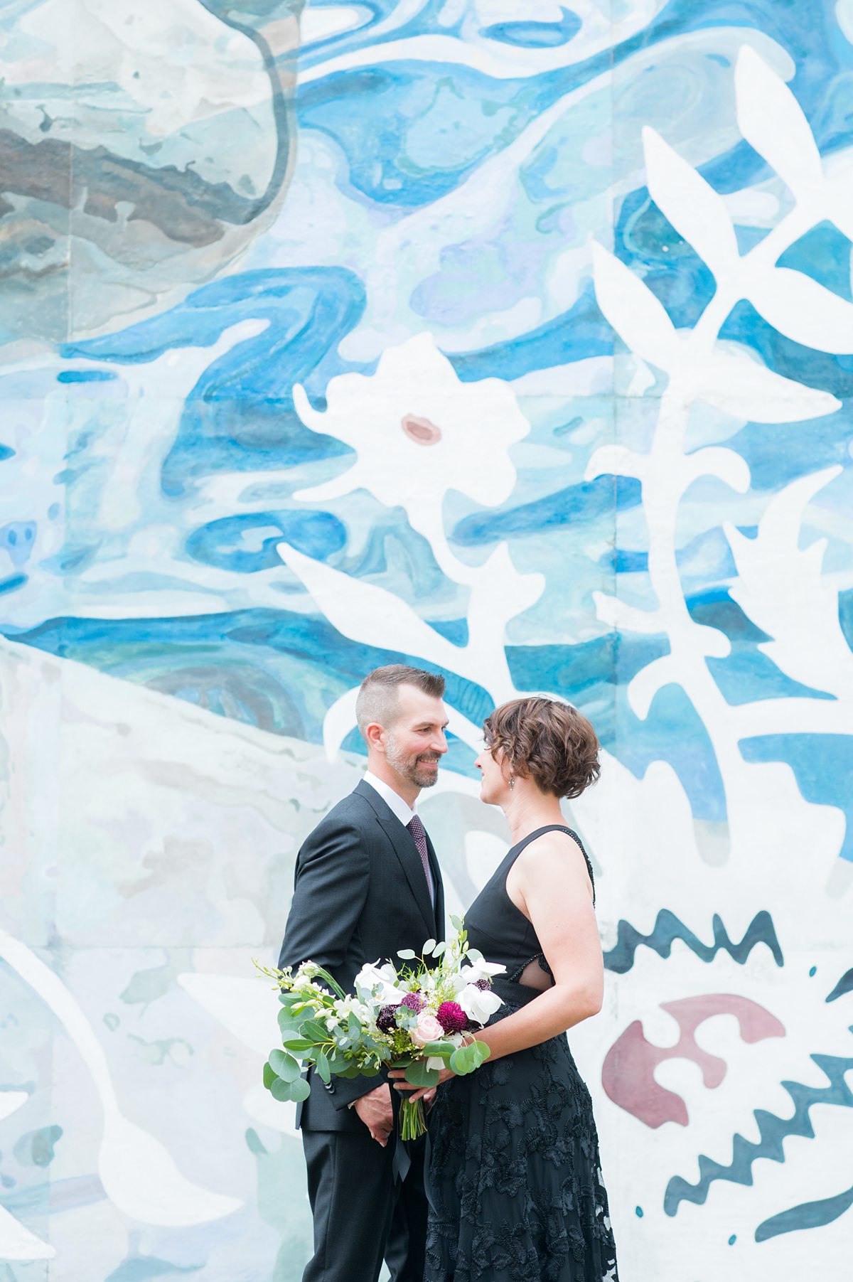 Bride and groom in front of a colorful mural.