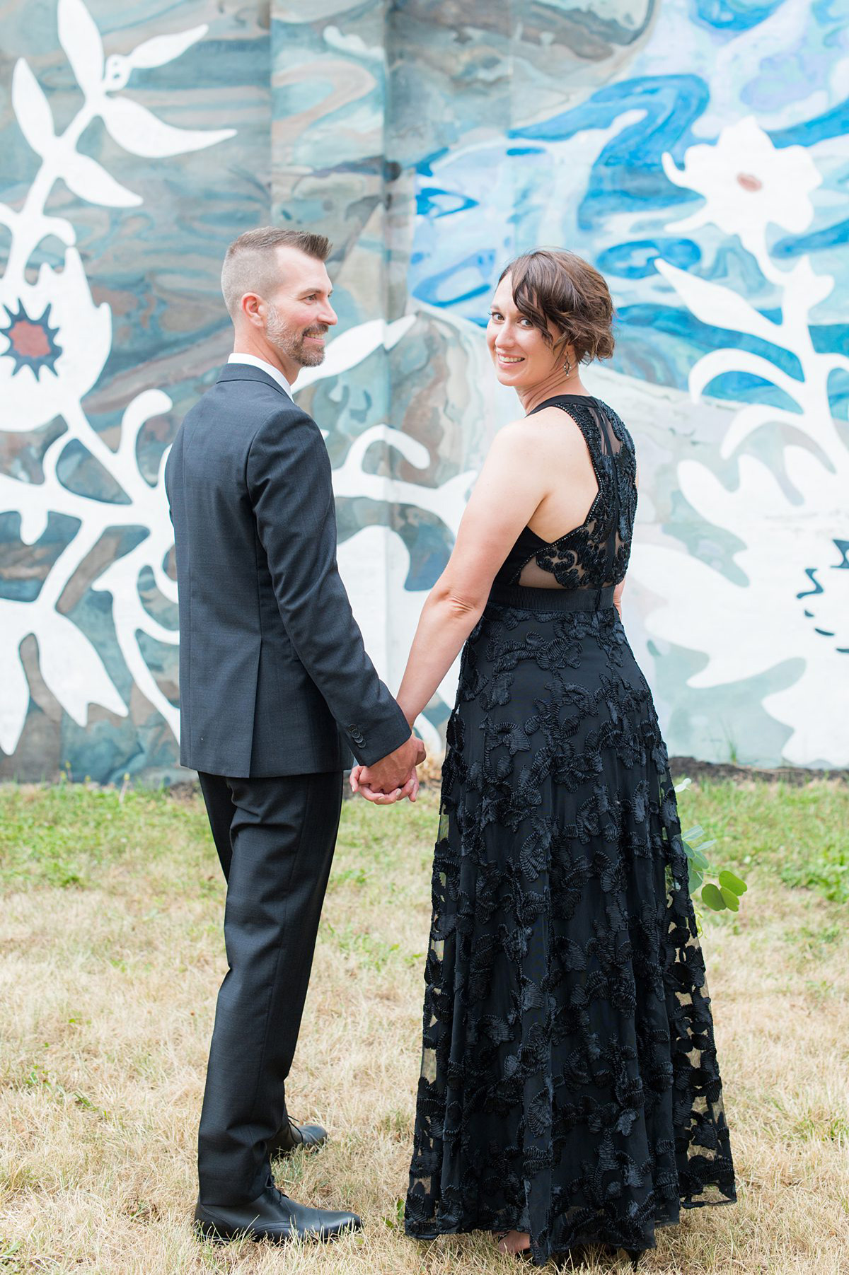 Bride and groom in front of a colorful mural.