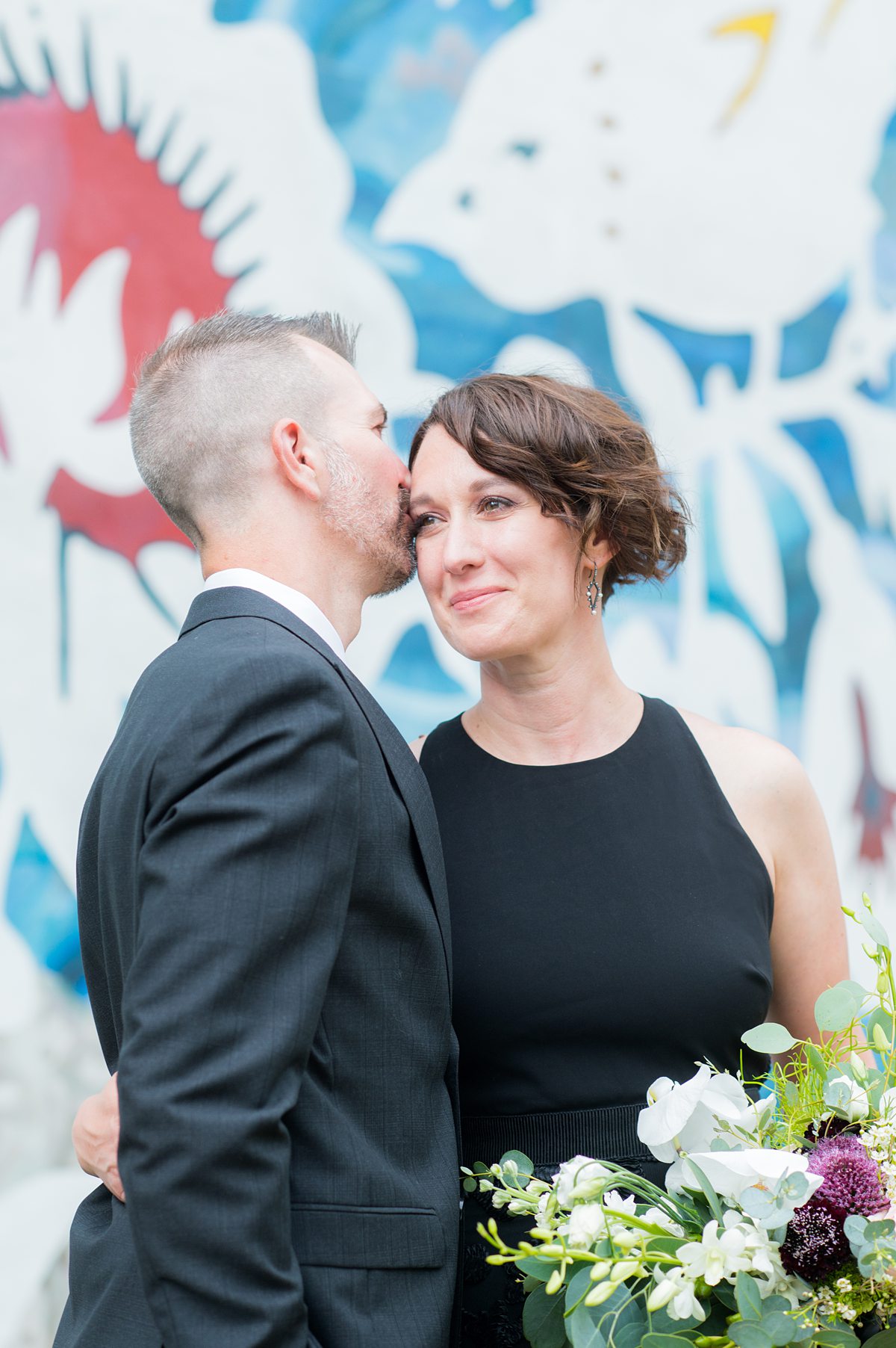 Bride and groom in front of a colorful mural.