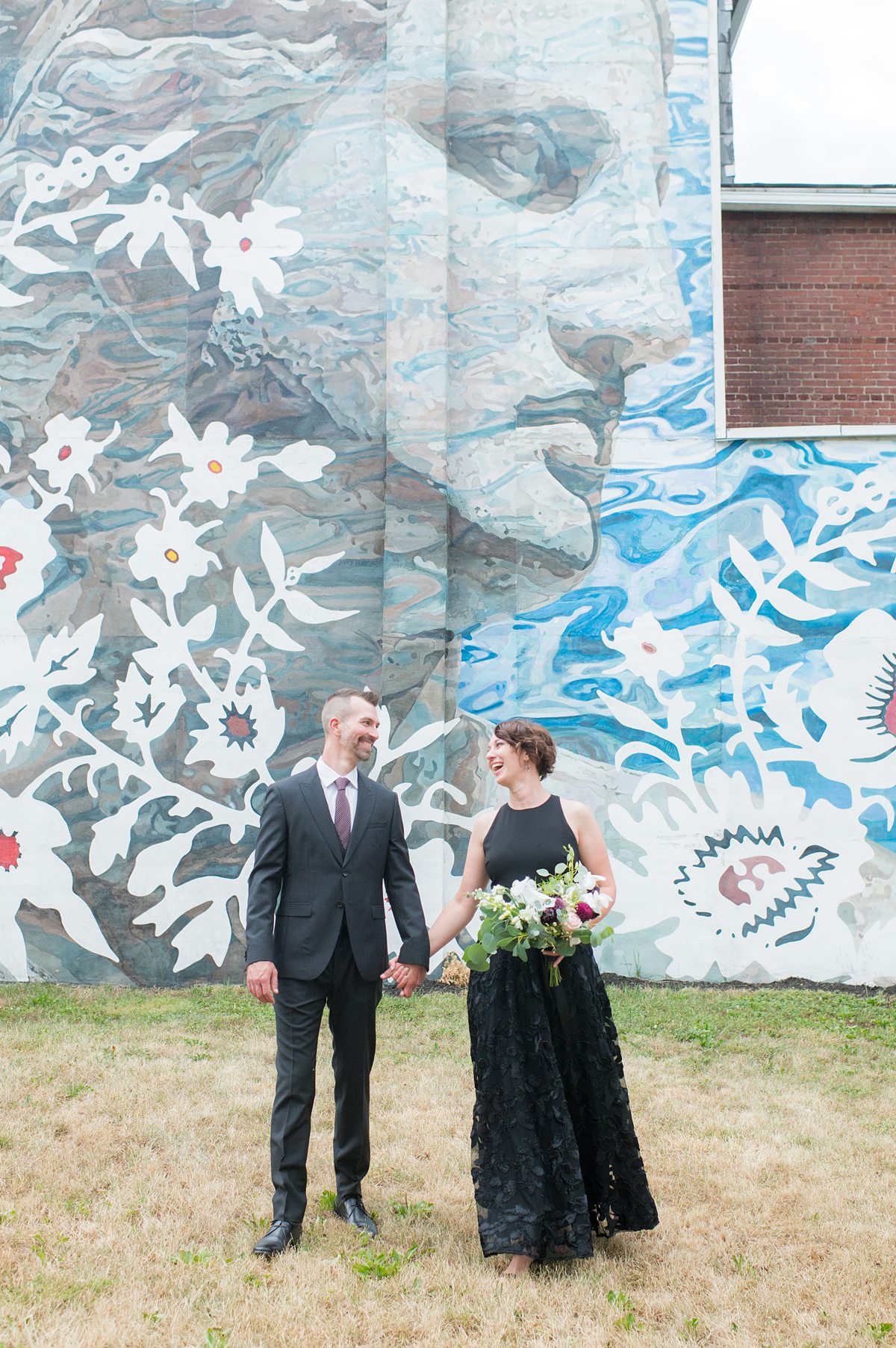 Bride and groom in front of a colorful mural.