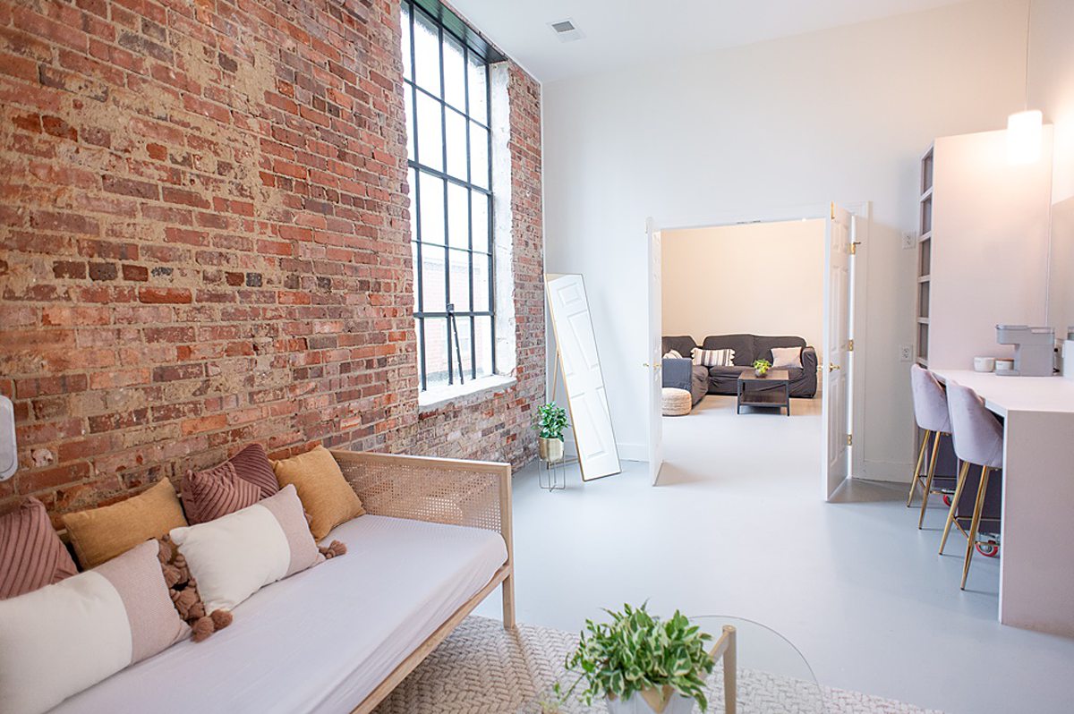 A room with a couch and brick wall on the left and a doorway into another room at The Graham Mill wedding venue in NC.