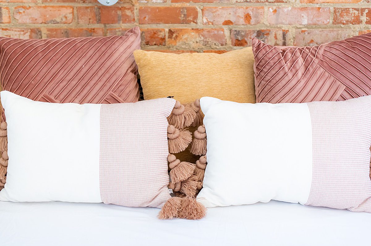 White, pink and yellow pillows with tassels on a couch at The Graham Mill in NC, a city wedding venue.