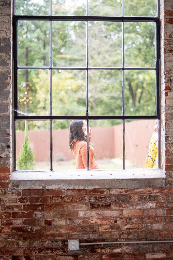 A woman in an orange shirt seen through the window of The Graham Mill in NC.