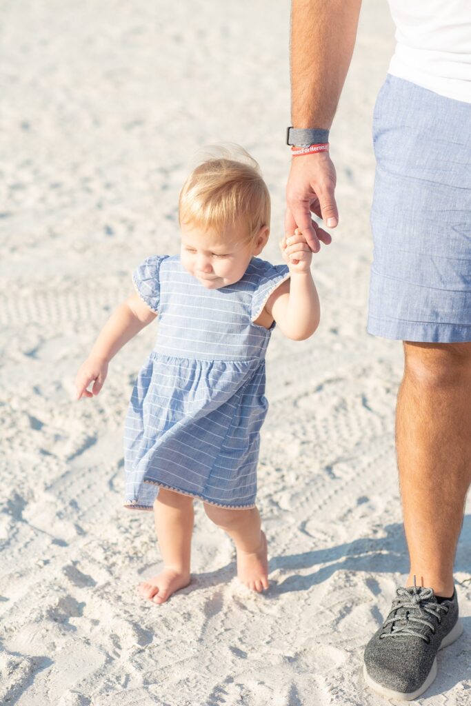 Toddler on a beach holding parents' hands on Marco Island. Family photos by Mikkel Paige Photography.