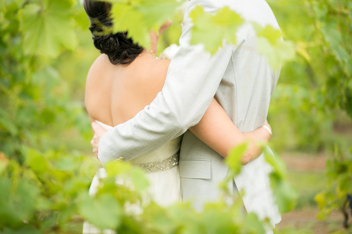Couple with their arms around each other in a vineyard.
