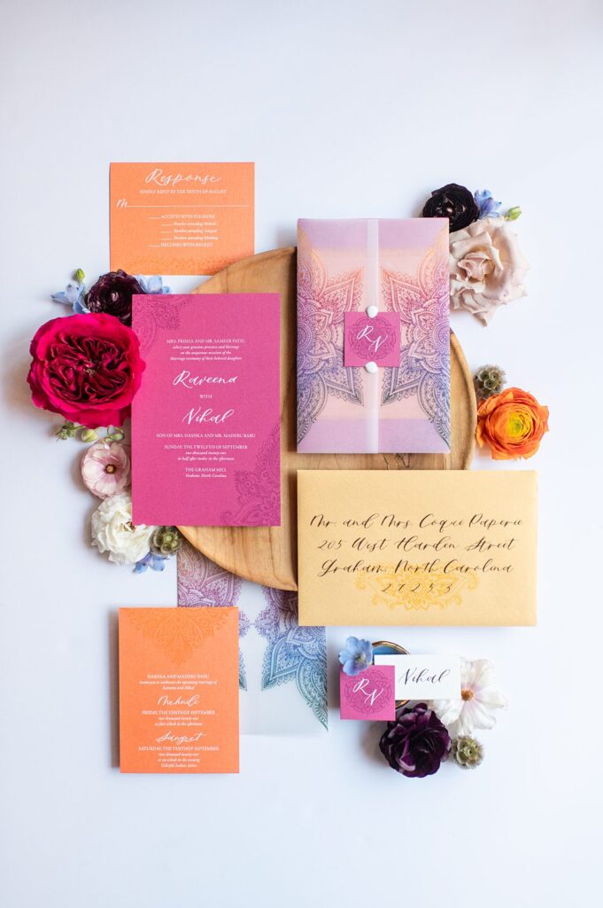 Colorful orange and pink stationery with vellum rainbow ombre pattern and flowers in a flat lay picture.