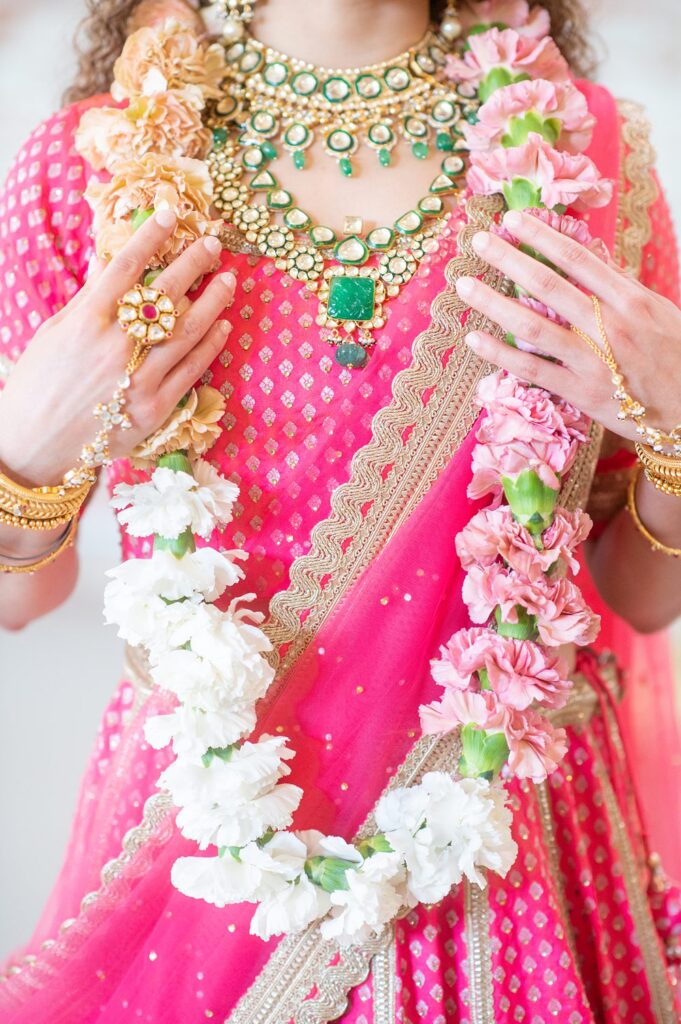 Flower garland around a bridesmaid in a pink Indian sari at a wedding in NC, at The Graham Mill, wearing a gold necklace.