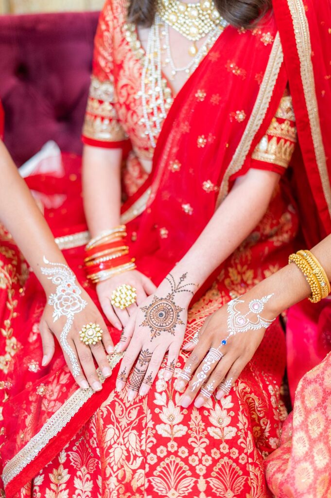 Mehndi party henna on the women's hands against red Indian attire. Wedding at The Graham Mill in NC with photos by Mikkel Paige.