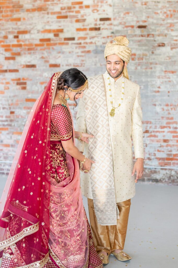 Bride and groom in Indian wedding attire in front of a brick wall at The Graham Mill wedding venue in NC. Photos by Mikkel Paige Photography.