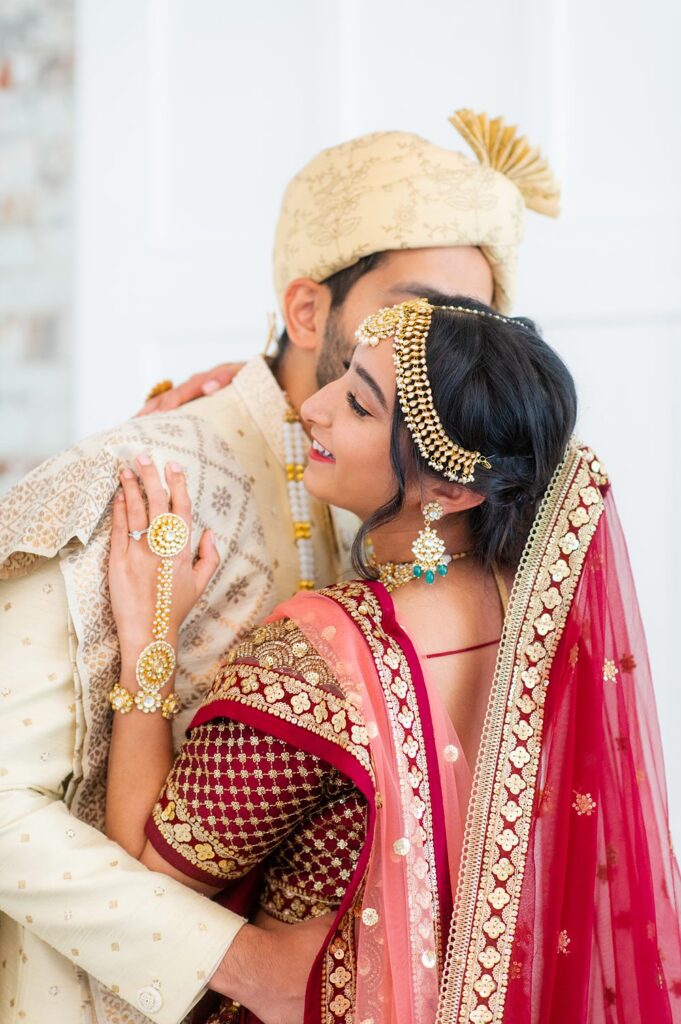 Bride and groom in Indian wedding attire in front of a white wall at The Graham Mill wedding venue in NC.