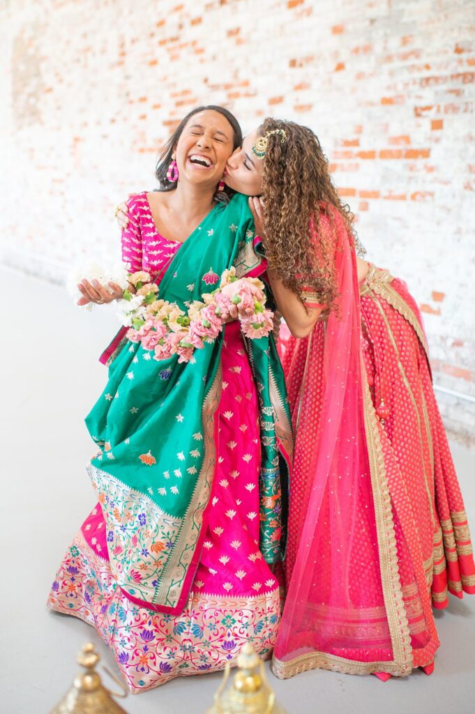 Two women in colorful Indian saris at a wedding in a playful image.