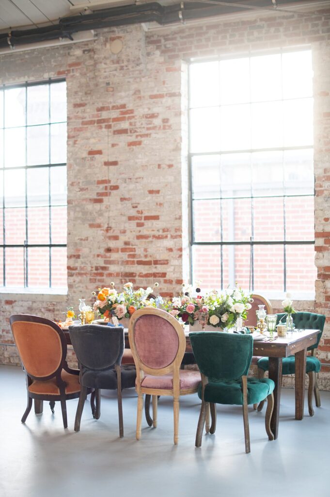 Colorful reception table with orange, blue, pink and green and colorful velvet chairs.