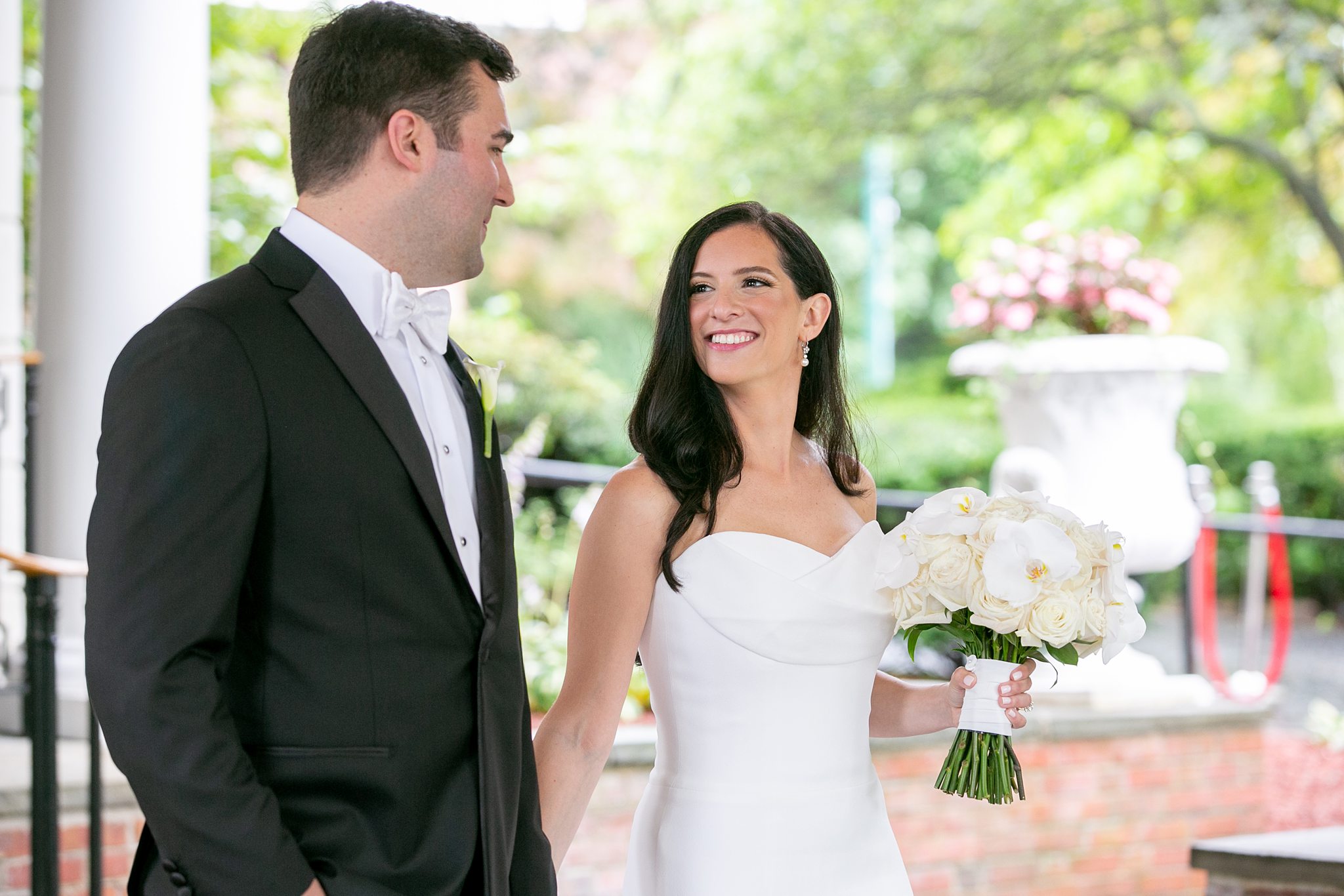 Rebecca and Dan, a bride and groom, at a wedding at The Carltun on Long Island, with a bouquet of white roses and orchids.