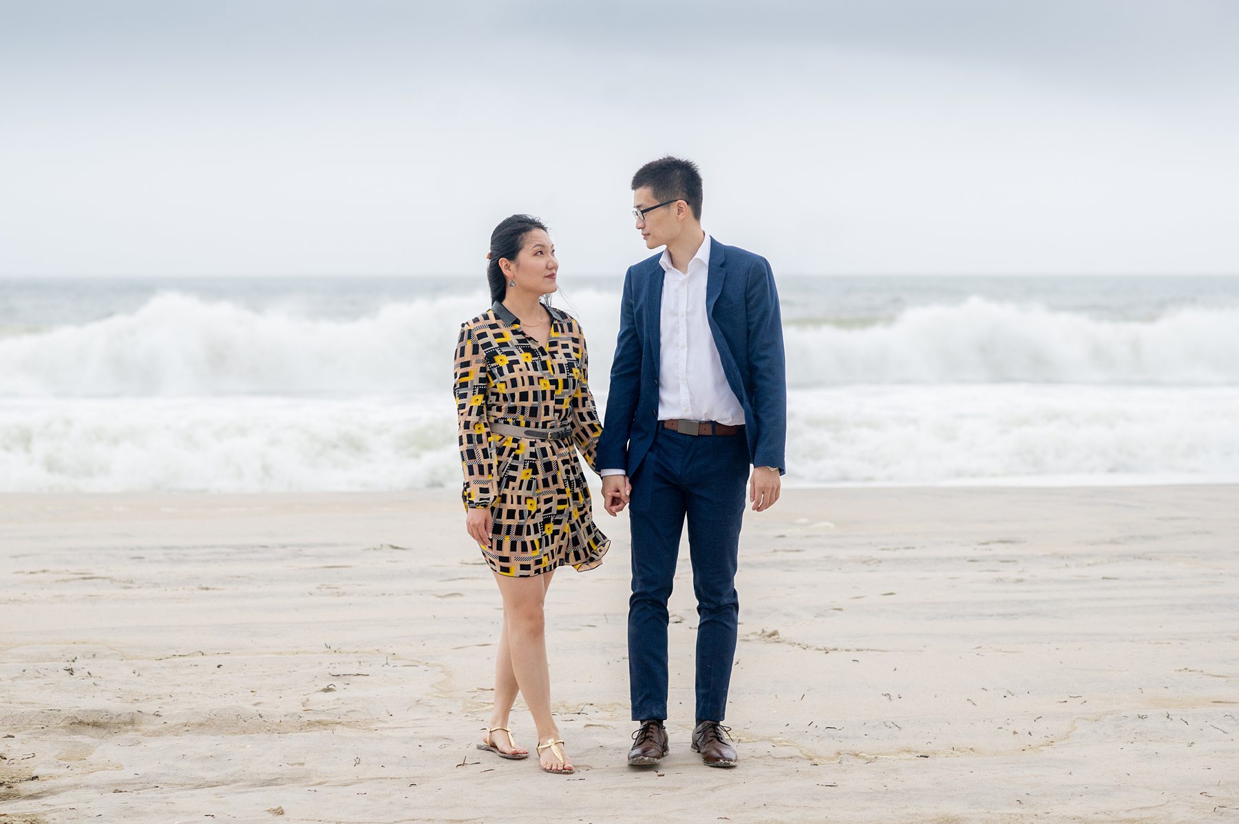 Photo of a couple in dress clothes with the ocean behind them for a proposal on Robert Moses State Park Beach on Long Island.