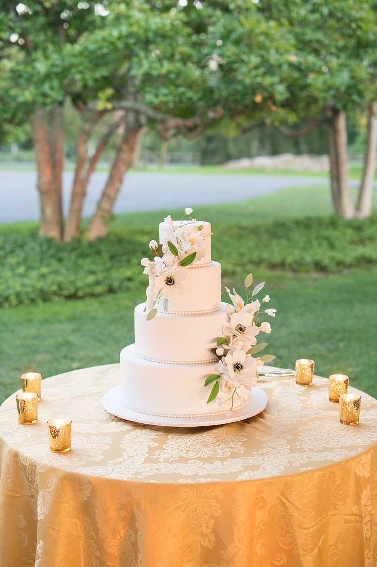 White four tier cake with fondant and gumpaste flowers at a wedding at Sleepy Hollow Country Club in New York.