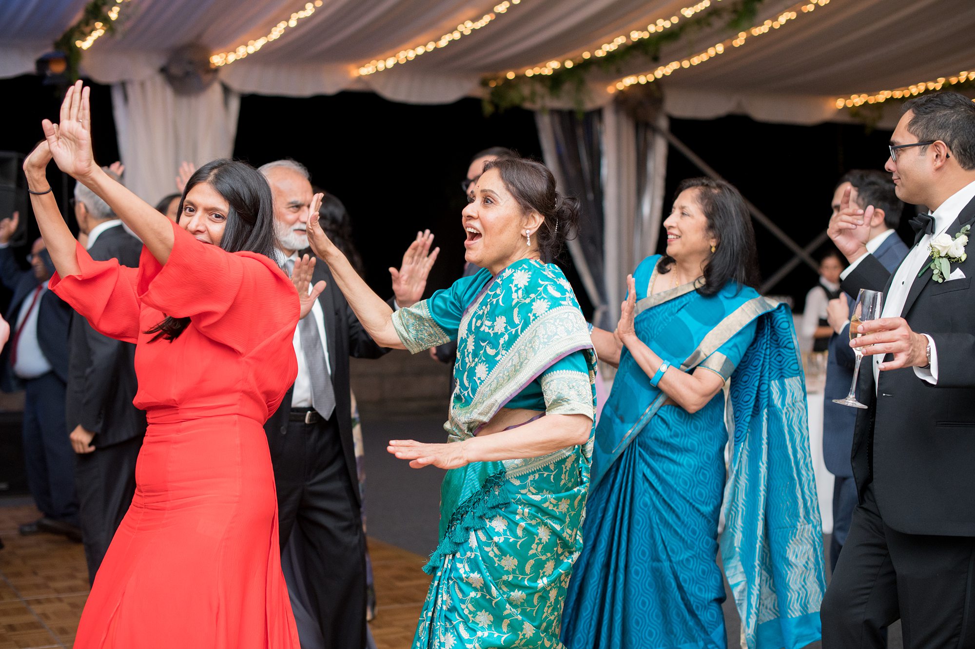 Indian wedding celebration and dancing with women in traditional saris.