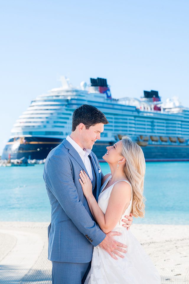 Bride and groom looking at each other with Disney Wish cruise ship in the background on Castaway Cay.