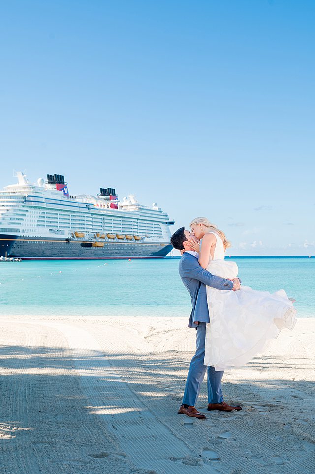Bride and groom on the beach with Disney Wish in the background for Castaway Cay wedding photos the day after their Disney Cruise Line celebration.