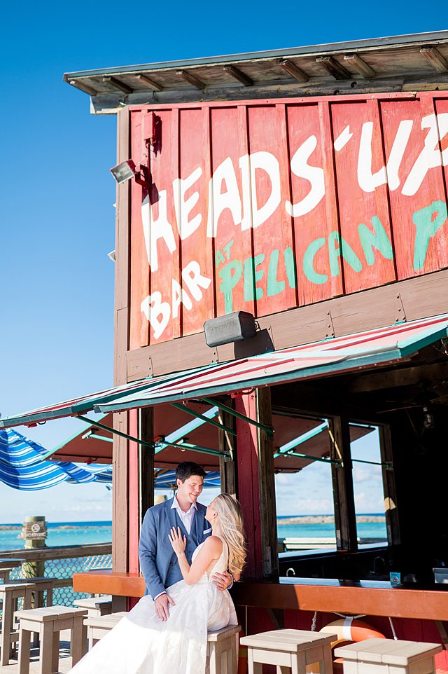 Bride and groom looking at each other near the turquoise water on Castaway Cay for wedding photos under Heads Up Pelican Bar. Pictures by Mikkel Paige Photography.