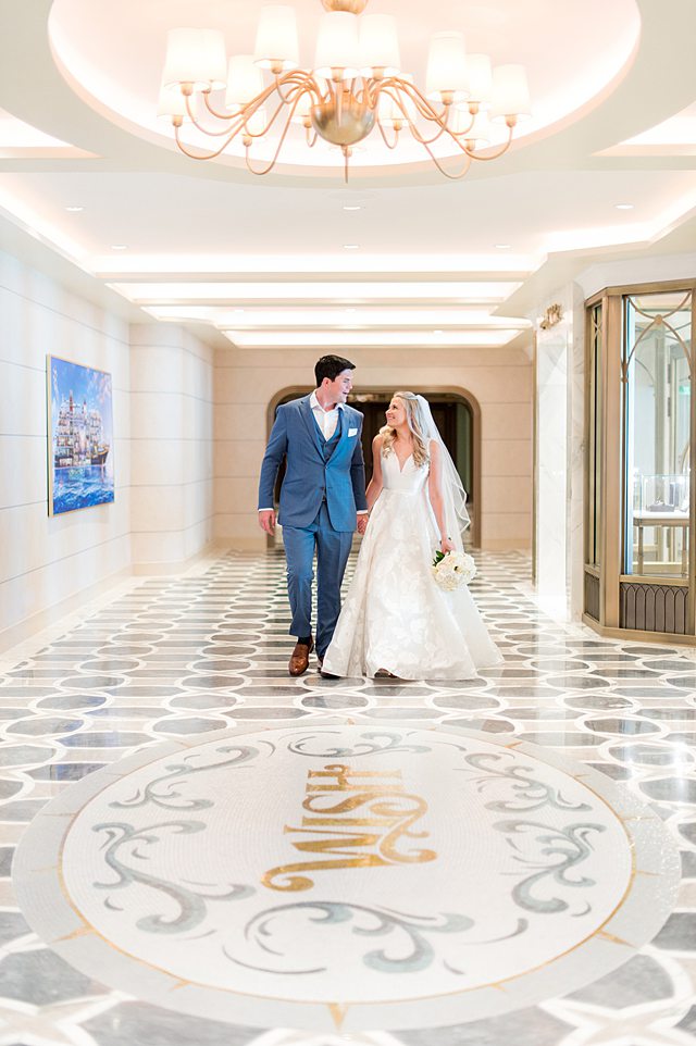 Couple walking in a marble tile hallways in their Disney Wish wedding photos by Mikkel Paige Photography, with "WISH" in the floor.