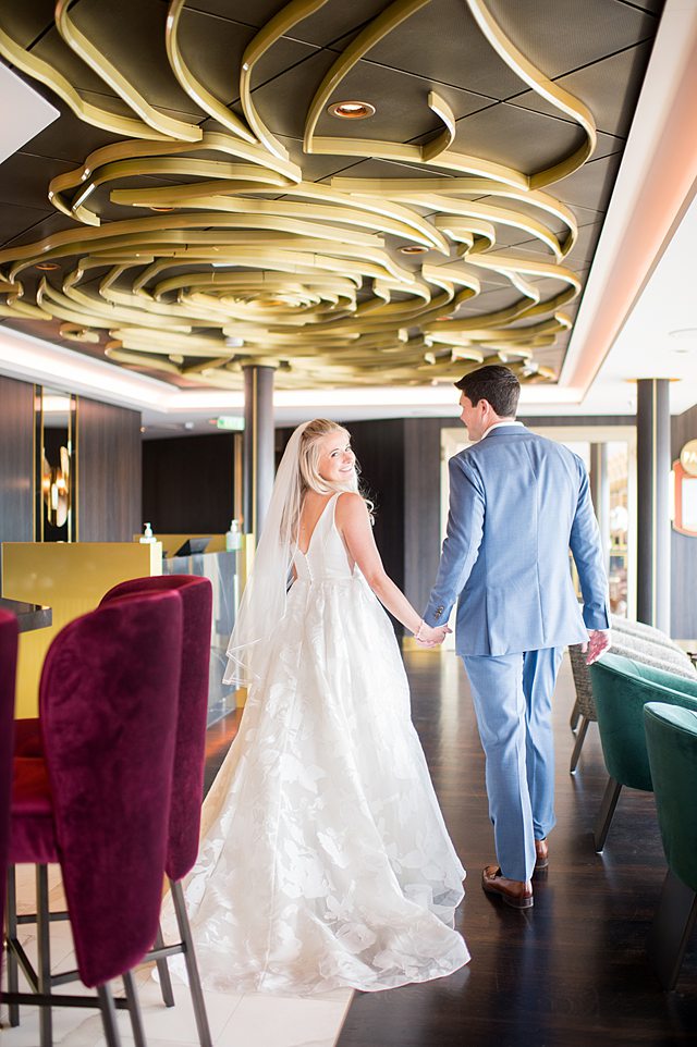 Bride looking over her shoulder at the camera in The Rose bar on Disney Wish in their Disney Cruise Line wedding photos by Mikkel Paige Photography.