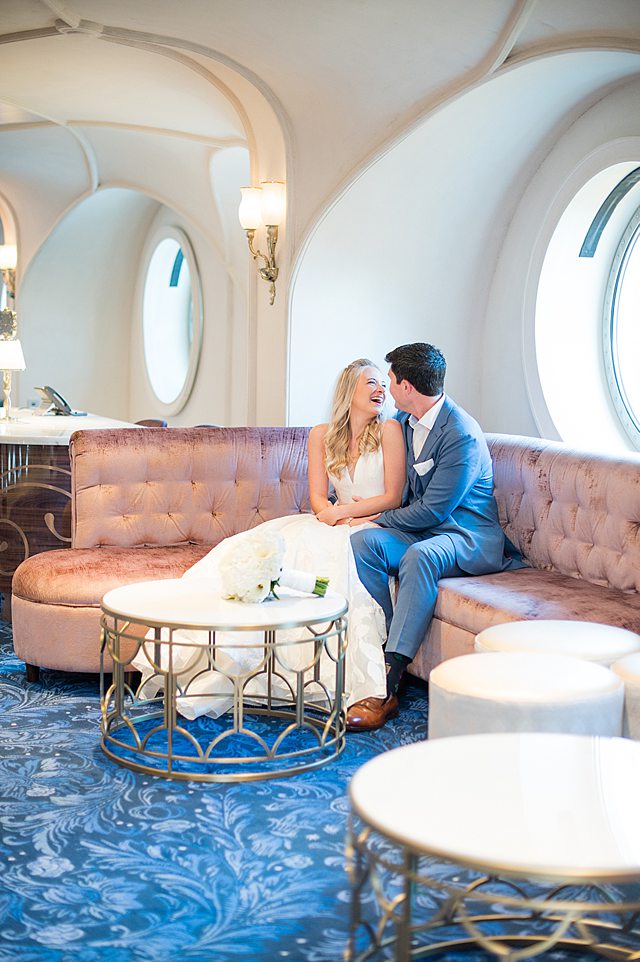 Disney Wish wedding photos by Mikkel Paige Photography of the bride and groom looking at each other on pink couches.