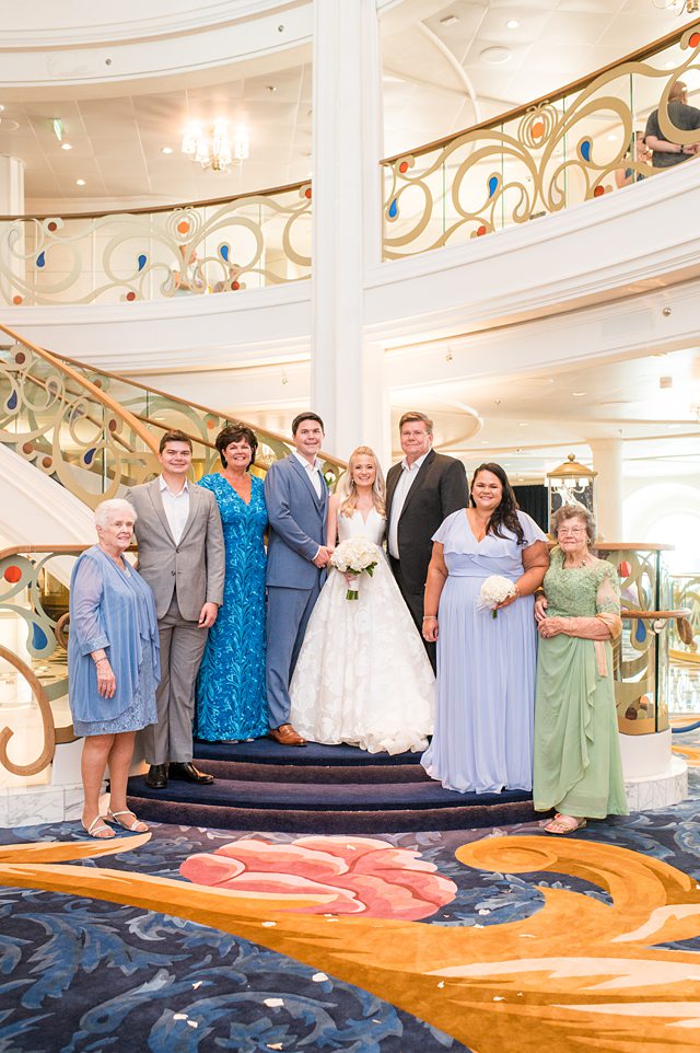 Family wedding photos on the stairs of the Grand Hall on a Disney Cruise Line wedding on Disney Wish with photos by Mikkel Paige Photography.