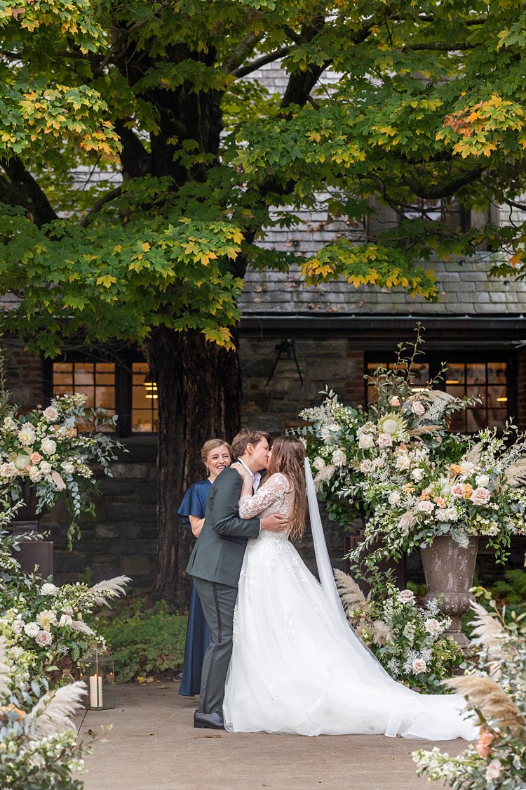 Ceremony kiss with flowers surrounding the brides for a fall wedding at Blue Hill Stone Barns.