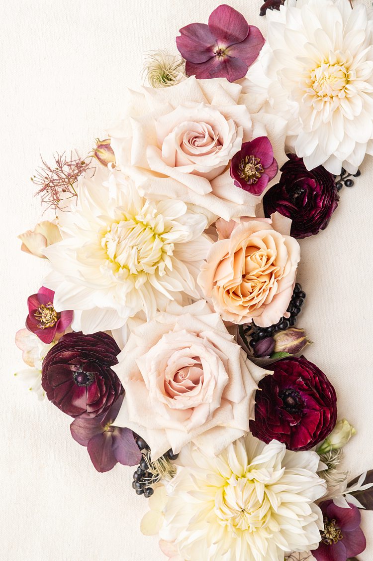 Flat lay of flowers by Mikkel Paige Photography from a fall wedding at Blue Hill Stone Barns with reds, peaches, pinks and off white colors.