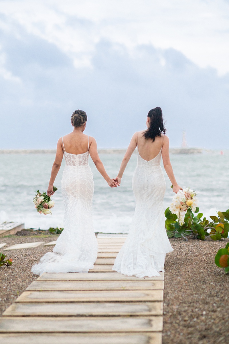 Two brides walking towards the ocean at their villa wedding at Casa de Campo in the Dominican Republic.