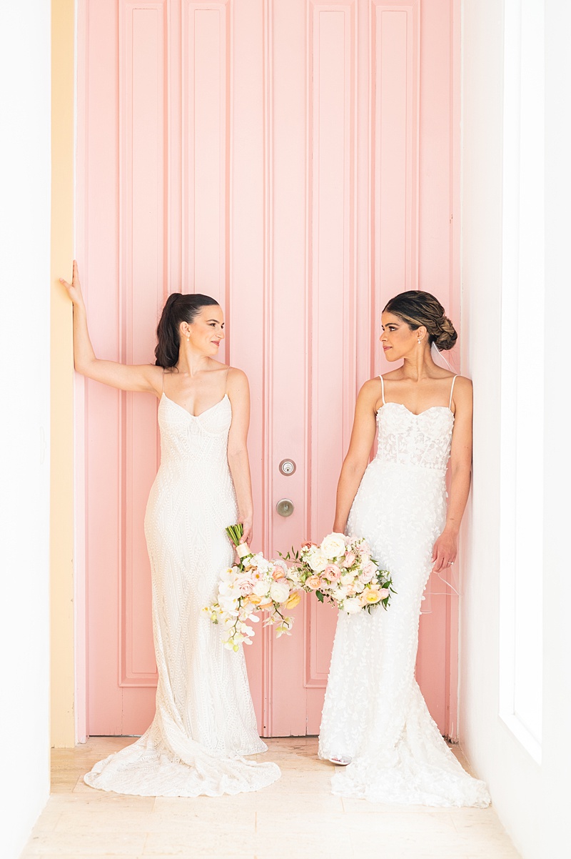 Two brides against a pink door at a private villa at Casa de Campo in the Dominican Republic.