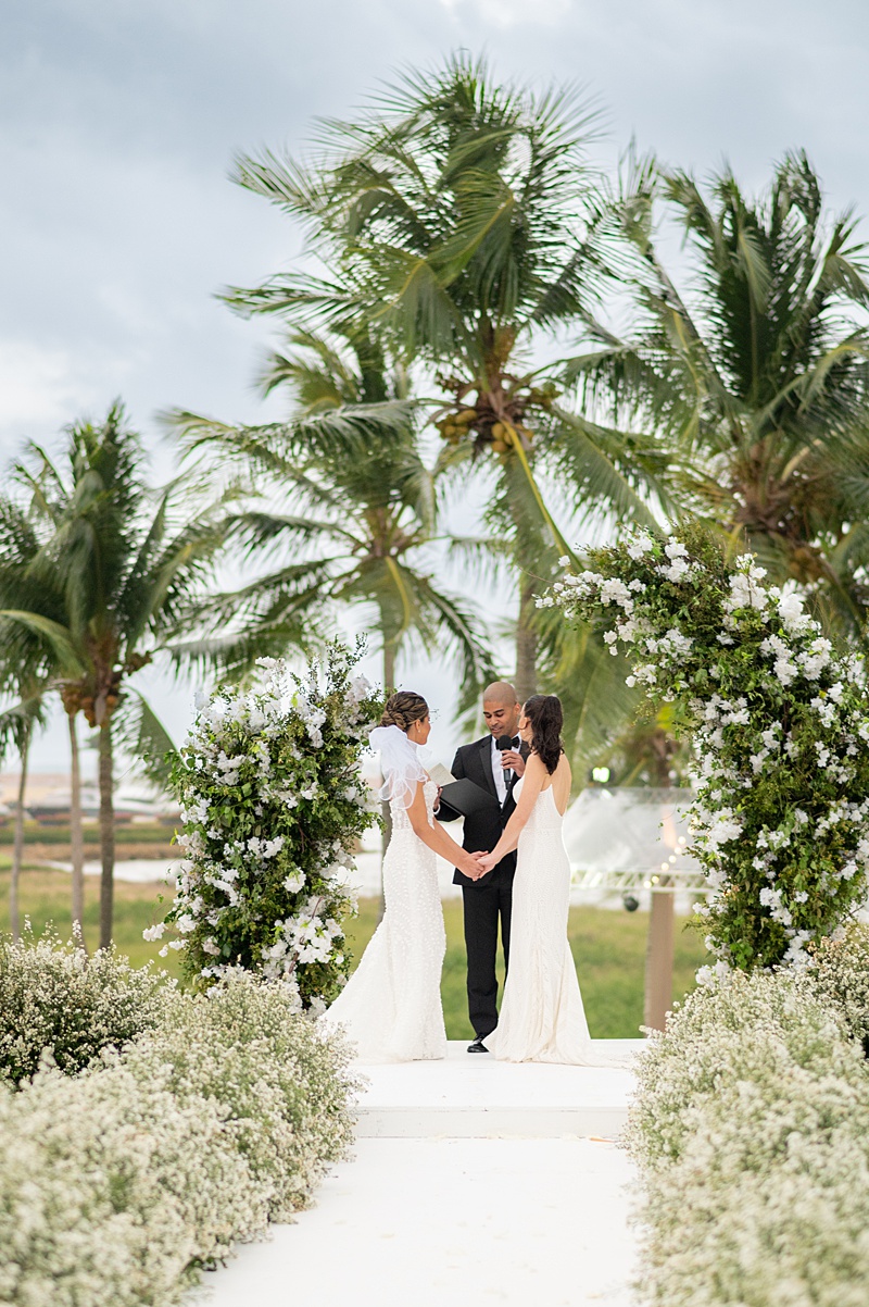 Ceremony with a floral-lined aisle and palm trees in the background at a villa at Casa de Campo in DR.