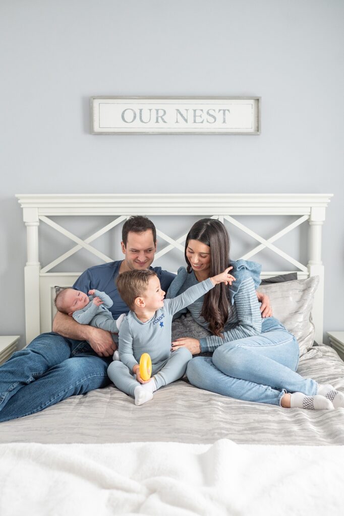 Family dressed in blue tones for a photography session at home on their bed.