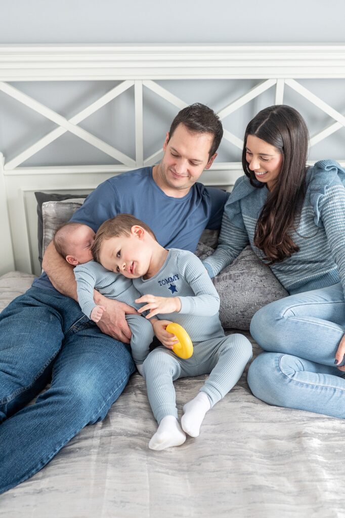 Family dressed in blue tones for a photography session at home on their bed.